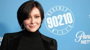 Shannen Doherty posing in front of a 90210 backdrop 