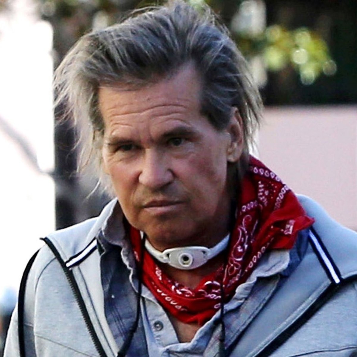 Val Kilmer posing with a red banana and his windpipe that he uses as a breathing aid due to his throat cancer