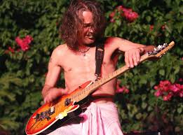 Eddie Van Halen rocking out on a guitar with a metal guitar pick in his mouth