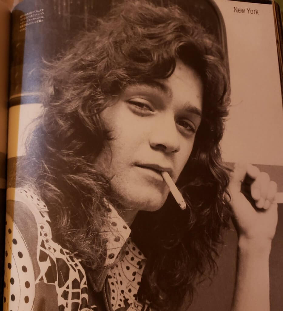 Eddie Van Halen smoking a cigarette at a younger age with longer and curly hair