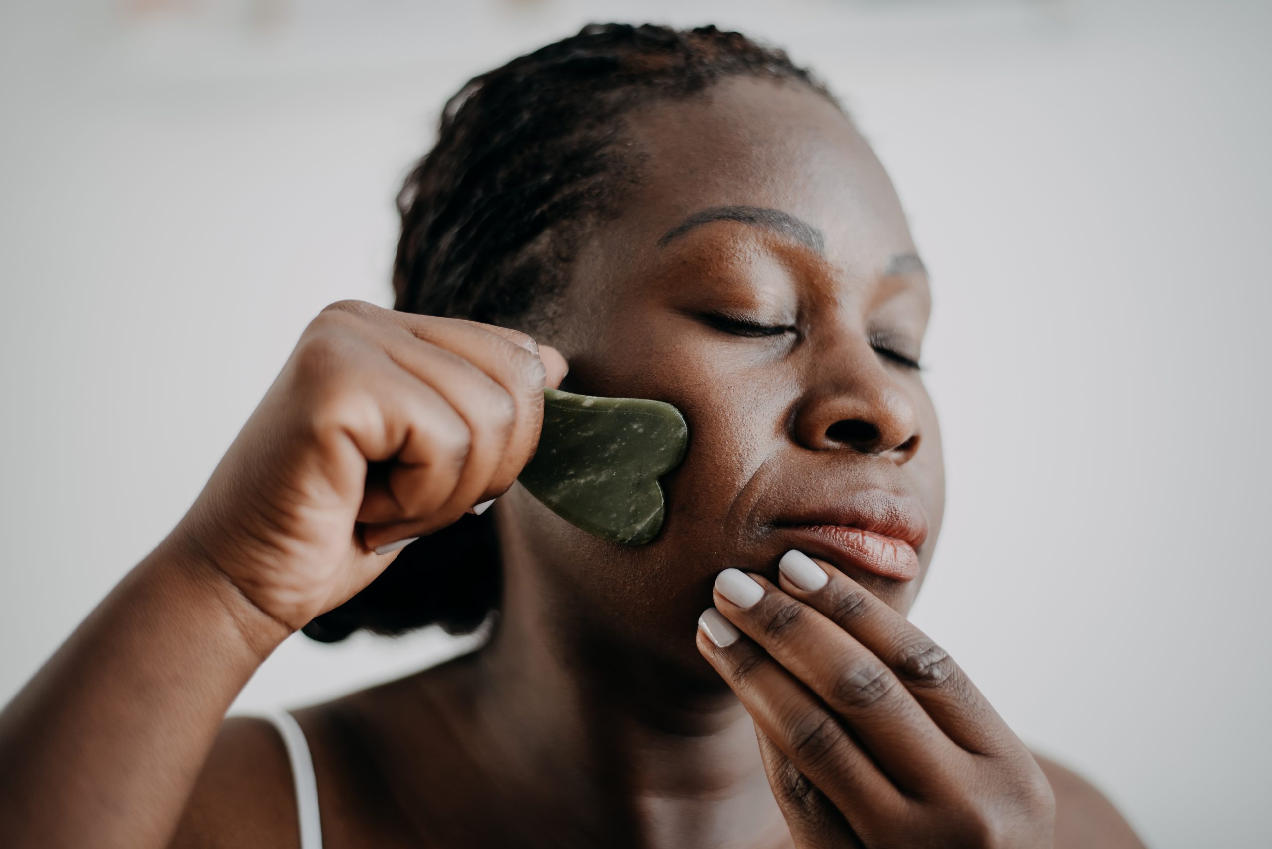 A woman demonstrates how a gua sha tool is used on the face. (Getty Images)